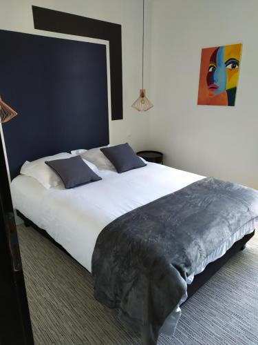 een slaapkamer met een groot wit bed met blauwe kussens bij Cocon au coeur du petit bayonne in Bayonne