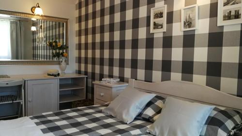 a bedroom with a checkered wall with a bed and a sink at Willa Łysica in Krynica Morska