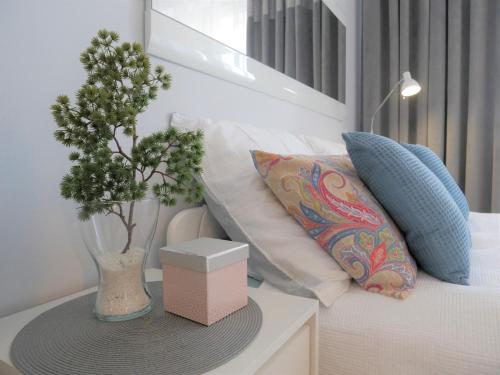 un letto bianco con cuscini e un vaso con una pianta di Apartament NA KLIFIE a Słupsk