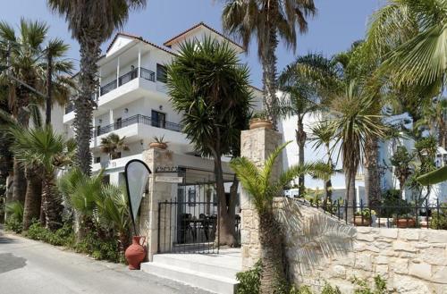 a white building with palm trees in front of it at Minoa Apartments in Amoudara Herakliou
