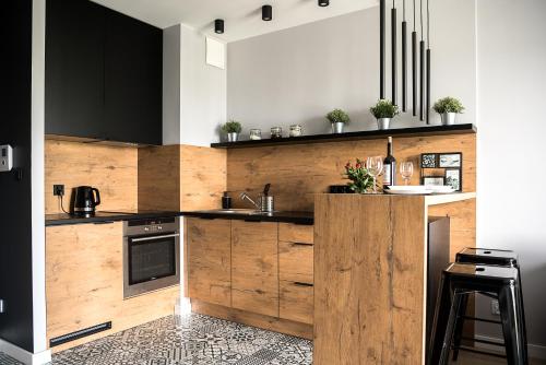 una cocina con armarios negros y de madera y fregadero en Wola Loft Apartment, en Varsovia