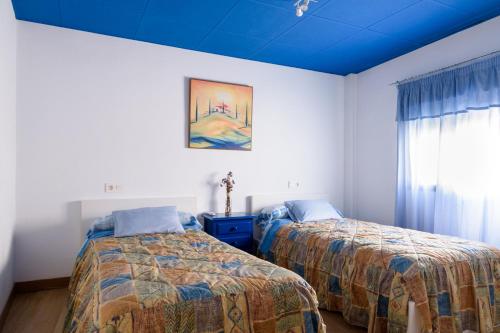 a bedroom with two beds and a blue ceiling at Casa de Chocolate in Martos