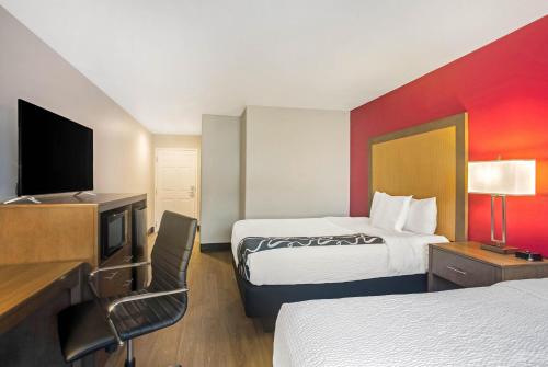 a hotel room with two beds and a flat screen tv at La Quinta by Wyndham Fort Smith in Massard