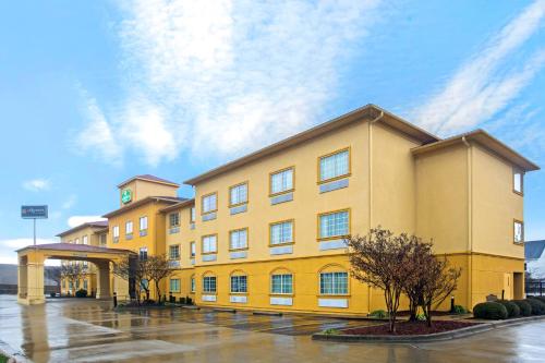 a hotel with a yellow building in a parking lot at La Quinta by Wyndham Fort Smith in Massard
