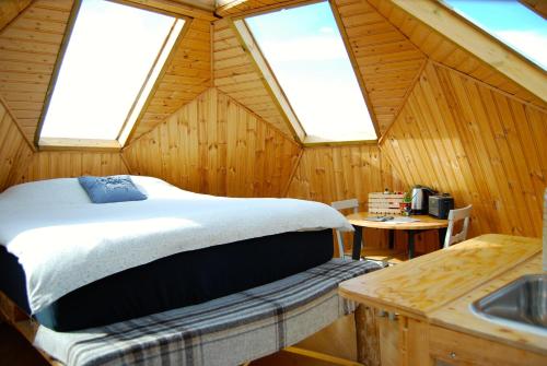 ein Schlafzimmer in einer Holzhütte mit einem Bett und einem Waschbecken in der Unterkunft Sky sighting Iglúhús - Stay'in Árbakki in Litli-Árskógssandur