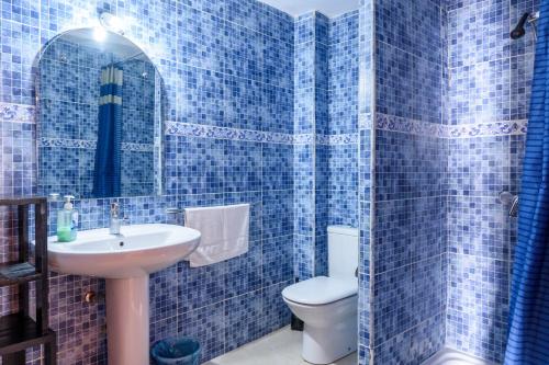 Baño de azulejos azules con aseo y lavamanos en Casa Patines, en Martos