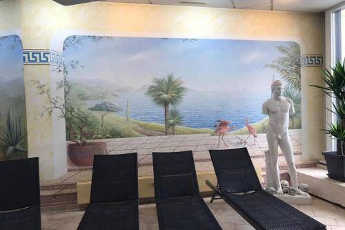 a mural in a room with chairs and a statue at Bayerwald Appartement in Sankt Englmar