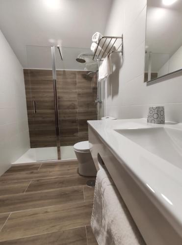 a white bathroom with a toilet and a sink at Hostal-Restaurante Paris in Forcarei