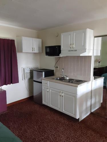 a kitchen with white cabinets and a sink and a refrigerator at WYE Motor Lodge Duncansville - Altoona in Duncansville