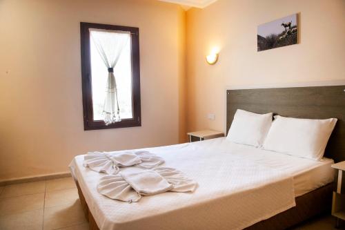Schlafzimmer mit einem Bett mit weißer Bettwäsche und einem Fenster in der Unterkunft Beyaz Konak Evleri in Datca