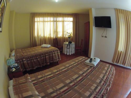 a hotel room with two beds and a flat screen tv at Hotel Alegria Nasca in Nazca
