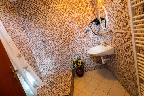 a tiled bathroom with a sink and a mirror at Penzion Kozí farma Nový Dvůr in Česká Lípa
