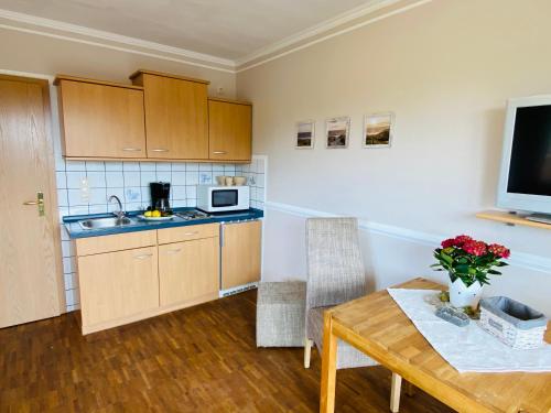 a kitchen with a table and a microwave and a television at Hasselberger Huus in Hasselberg