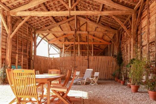 Gîte rural Aqui-naut في Montesquieu-Volvestre: حظيرة خشبية فيها طاولة وكراسي