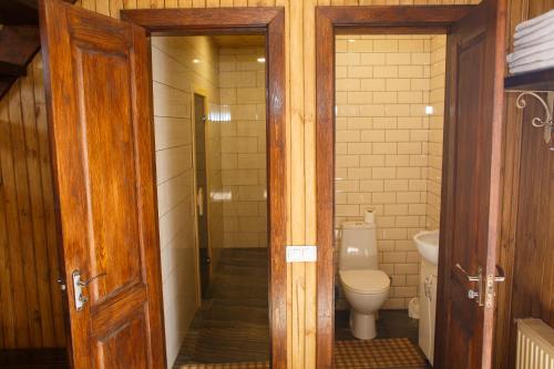 a bathroom with a toilet and a glass door at Комплекс На Дачі in Vyshpolʼ