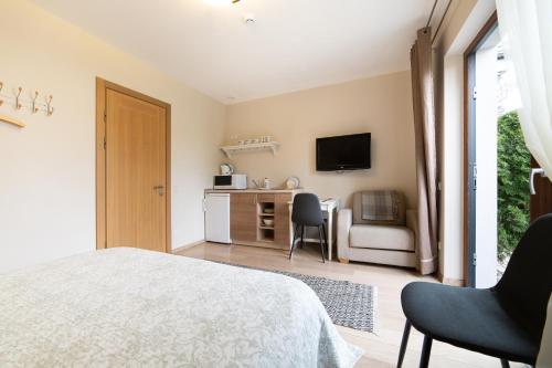 a bedroom with a bed and a desk with a tv at Rasos Vila in Palanga