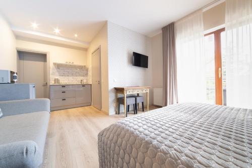 a bedroom with a bed and a desk and a kitchen at Rasos Vila in Palanga