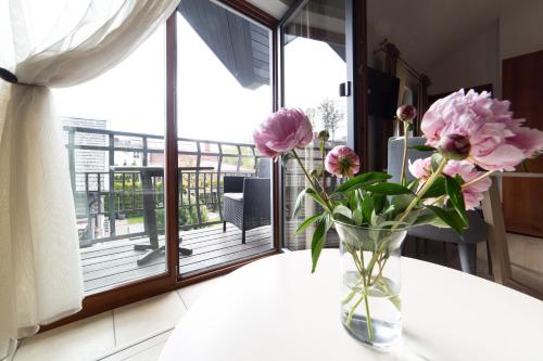 a vase with pink flowers on a table with a window at Rasos Vila in Palanga
