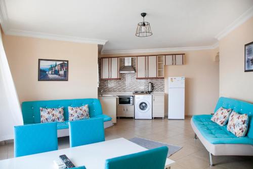 a living room with blue chairs and a kitchen at Beyaz Konak Evleri in Datca