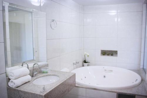a white bathroom with a tub and a sink at HOTEL VINTE UM in Ceilândia