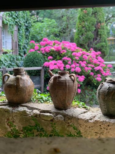 three clay vases sitting on a wall with pink flowers at Le Moulin du Roc in Brantôme