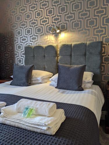 a bedroom with a large bed with blue pillows at The Wildings Hotel & Tudno's Restaurant in Llandudno