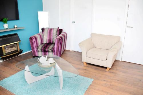 uma sala de estar com duas cadeiras e uma mesa de vidro em 7SM Dreams Unlimited Serviced Accommodation- Stanwell-Staines-Heathrow em Stanwell