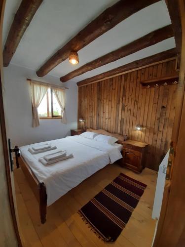 a bedroom with a large bed with a wooden wall at Семеен хотел Скендерова Къща in Leshten