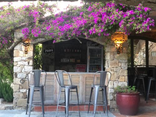 a group of chairs in front of a bar with purple flowers at Hôtel Casa Rossa & Spa in LʼÎle-Rousse