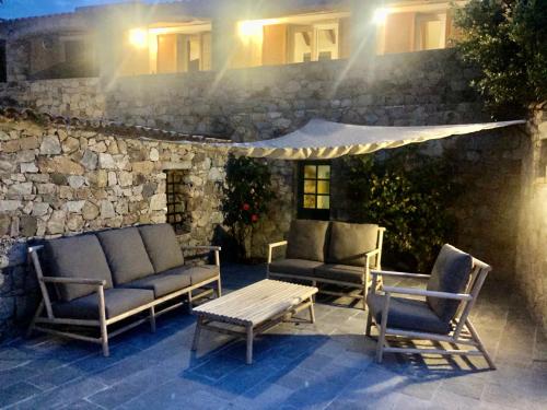 a patio with two chairs and a bench and a table at Hôtel Casa Rossa & Spa in LʼÎle-Rousse