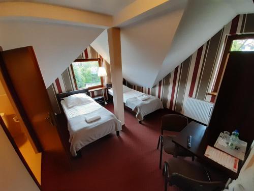 ズギェシにあるRoute One - Restauracja & Pokoje Hoteloweのベッド2台、テーブルと椅子が備わるホテルルームです。
