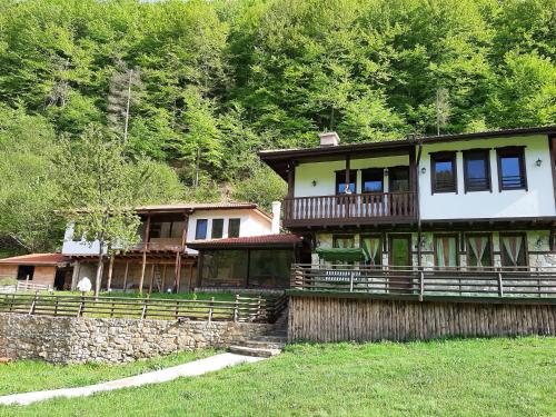 a large house with a stone wall at Къща за гости "Мегдана на Чаршията" in Smilyan