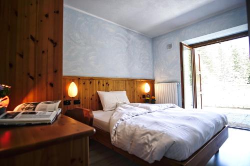 a bedroom with a bed and a desk with a laptop at Hotel Gembro in Chiesa in Valmalenco