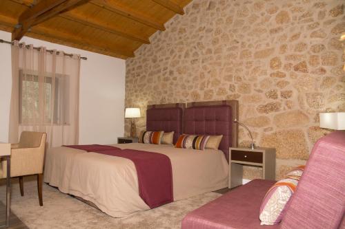 a bedroom with a large bed and a stone wall at Casas do Regato in Castelo Branco