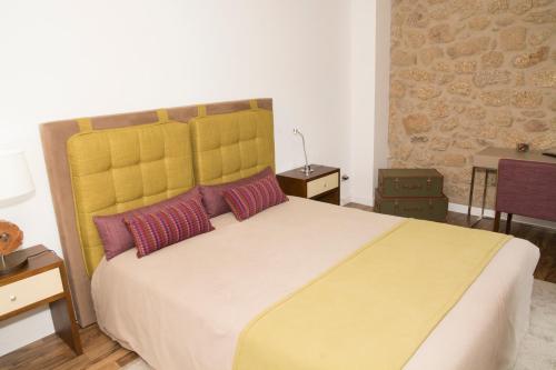 a bedroom with a large bed with two red pillows at Casas do Regato in Castelo Branco