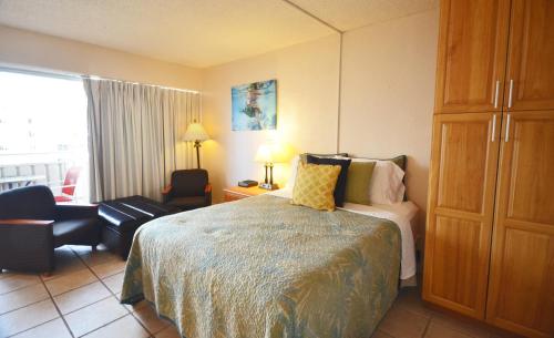 ein Hotelzimmer mit einem Bett und einem Stuhl in der Unterkunft Sea Shore 75 Steps from Waikiki Beach and Sleeps 1 - 3! in Honolulu