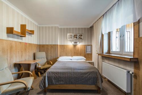 a bedroom with a bed and a table and a chair at Pokoje Gościnne i Apartamenty Krupówki 19 in Zakopane