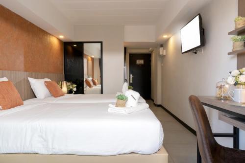 a bedroom with a bed and a desk and a television at The Home Hotel SHA in Bangkok