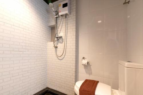 a white bathroom with a shower with a toilet at The Home Hotel SHA in Bangkok