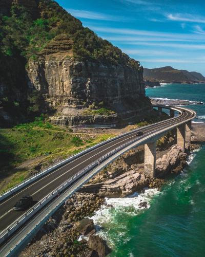 a bridge over the ocean next to a mountain at Argo Apartments in Wollongong