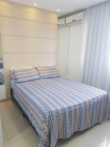 um quarto com uma cama com um cobertor azul e branco em Rio Centro - Barra da Tijuca - Recreio - Praia no Rio de Janeiro
