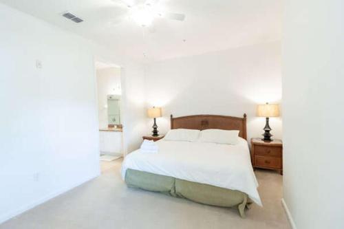 a white bedroom with a bed and two lamps at 5min Universal Spacious Condo VC101 in Orlando