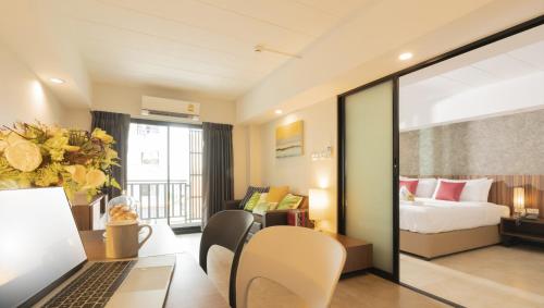 a hotel room with a bed and a desk with a laptop at The Home Hotel SHA in Bangkok