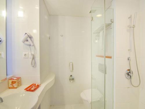 een badkamer met een douche, een toilet en een wastafel bij HARRIS Hotel and Conventions Denpasar Bali in Denpasar