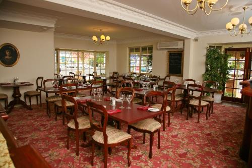 comedor con mesas y sillas de madera en Australian Heritage Motor Inn, en Dubbo