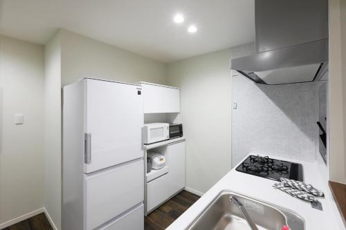 a kitchen with a white refrigerator and a sink at コンドミニアムHARU 那覇県庁前 202 in Naha