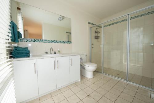 a white bathroom with a shower and a toilet at Ashendens at Penneshaw in Penneshaw