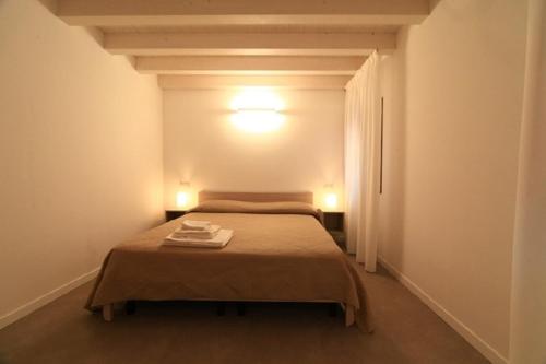 Un dormitorio con una cama en una habitación blanca. en Casa alla Torre, en Chioggia
