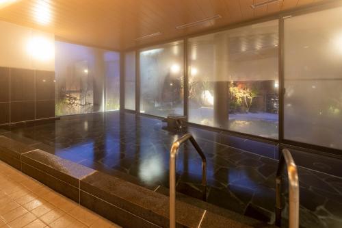 a jacuzzi tub in a room with windows at Izumo Yumuraonsen Seiranso in Unnan