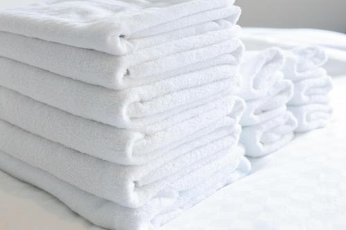 a stack of white towels on a white plate at NexStay HOUSE Osaka West in Osaka